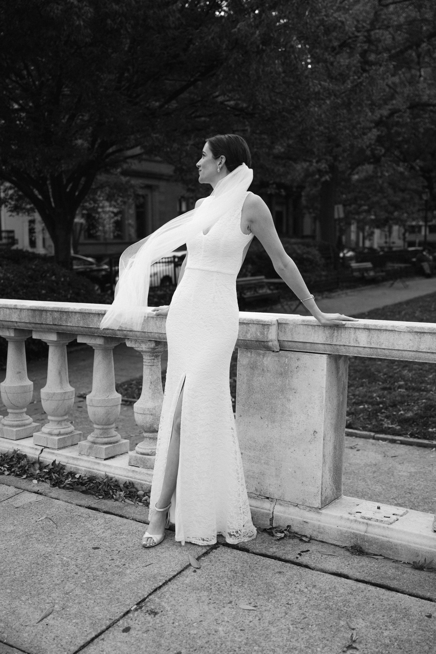 Artistic black and white wedding photo featuring a stone balustrade and elegant poses.