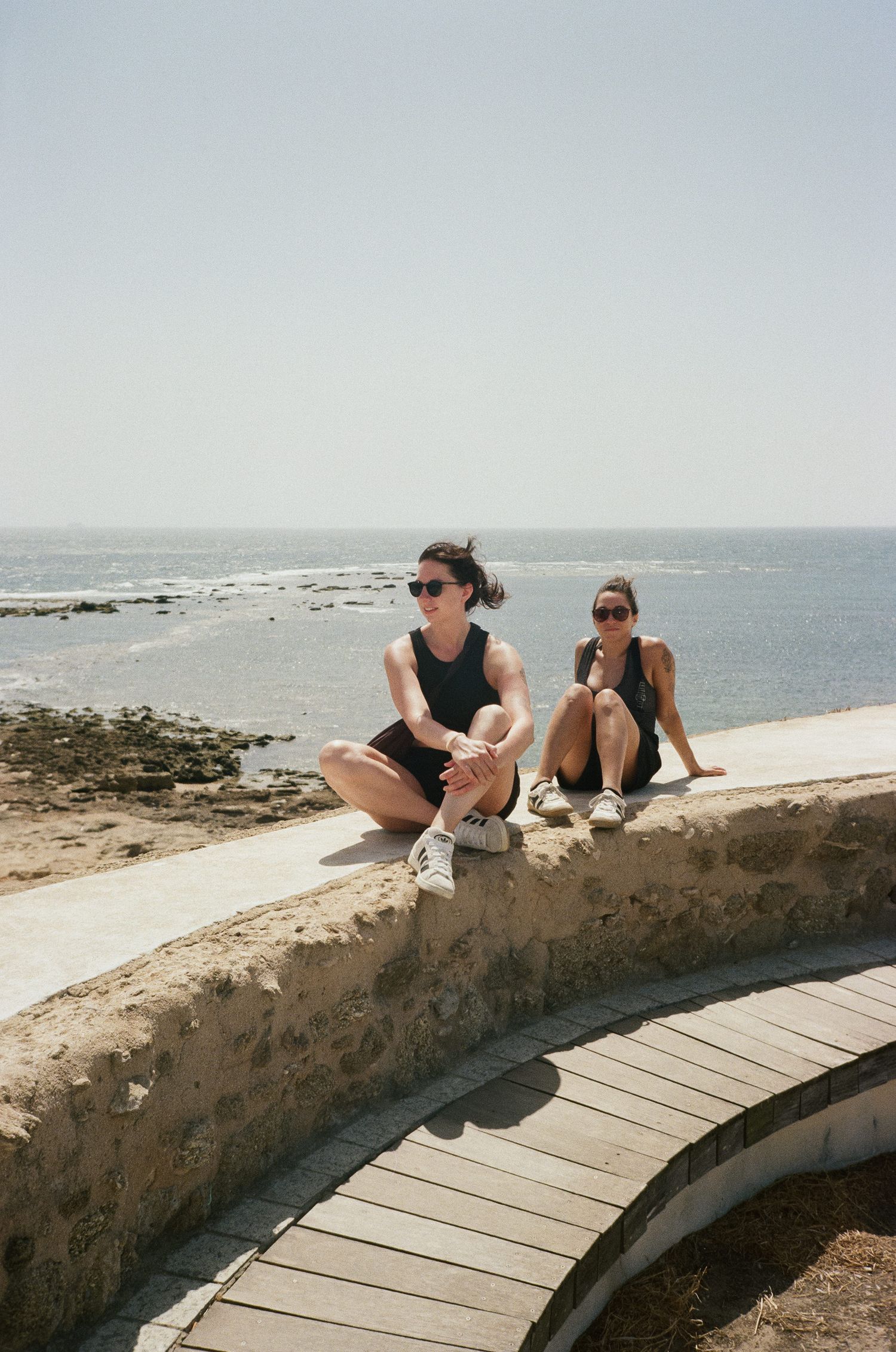 Stone walkway along the Mediterranean coast with people enjoying the ocean view.
