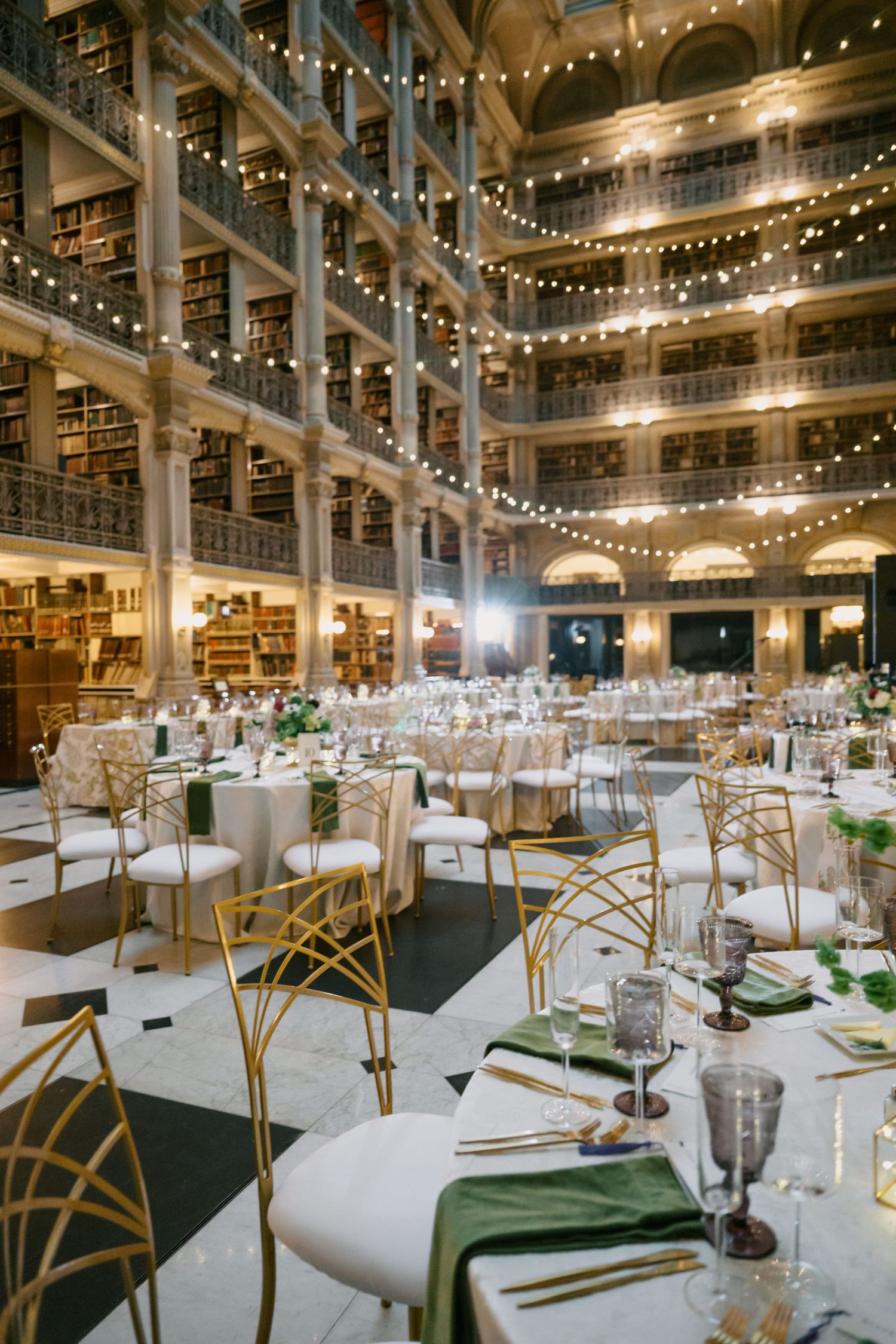 Library venue decorated for wedding reception with string lights and elegant table settings.