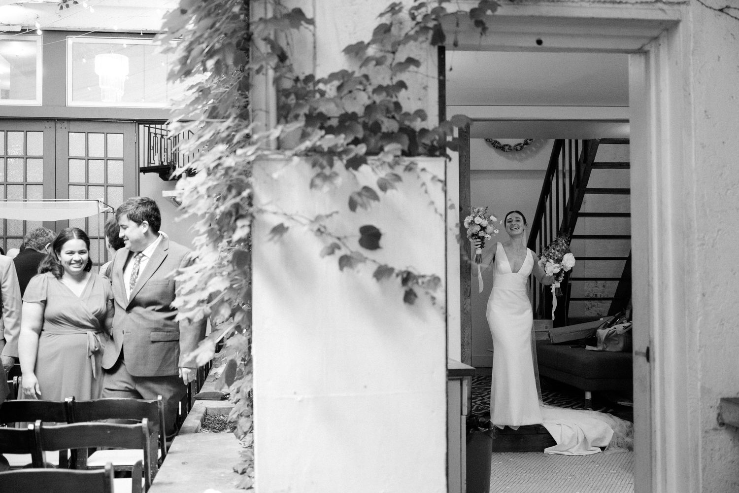 Black and white wedding photo capturing moments at an outdoor venue with architectural columns.