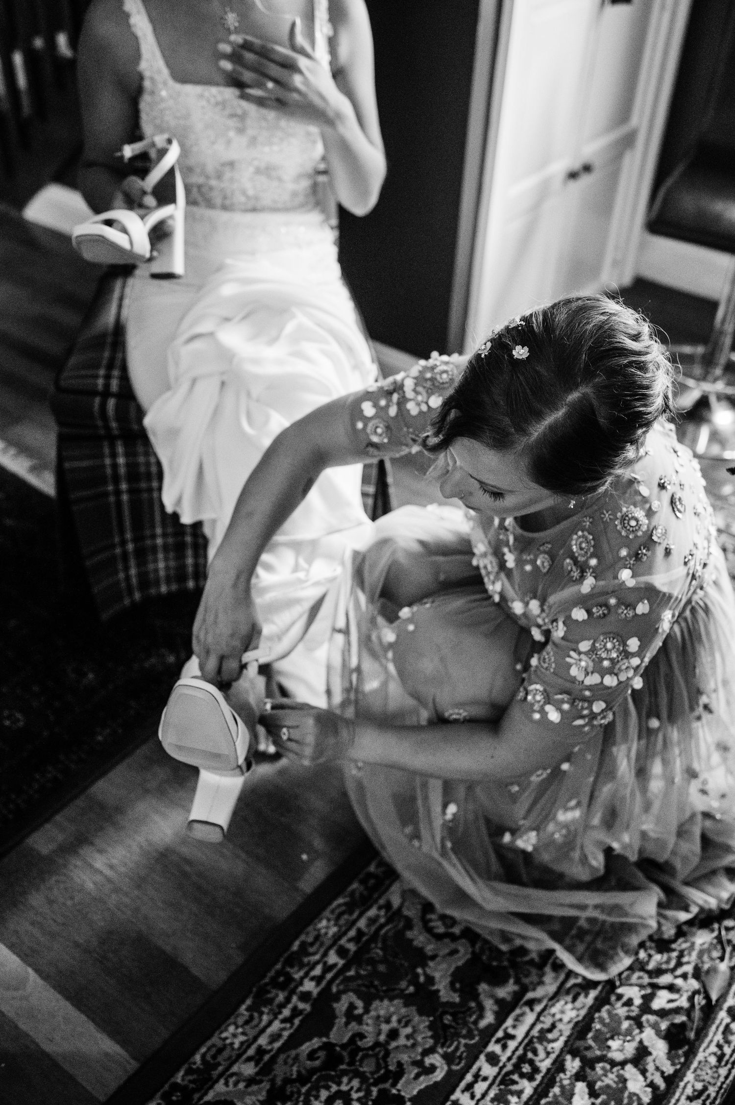 Black and white photo of wedding preparations showing dress details and final touches.