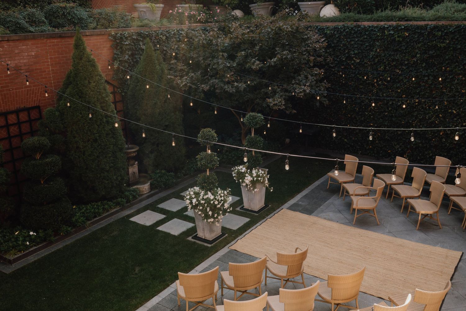 An outdoor event space with string lights and arranged chairs at dusk.