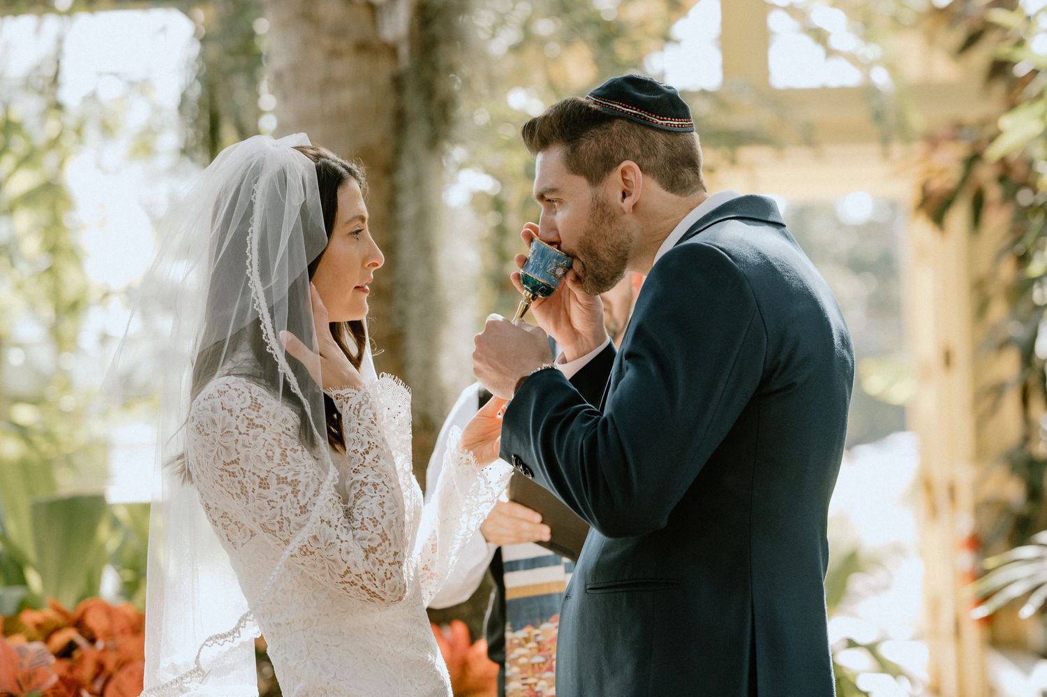 Couple sharing emotional moment during wedding ceremony in sunlit garden setting.