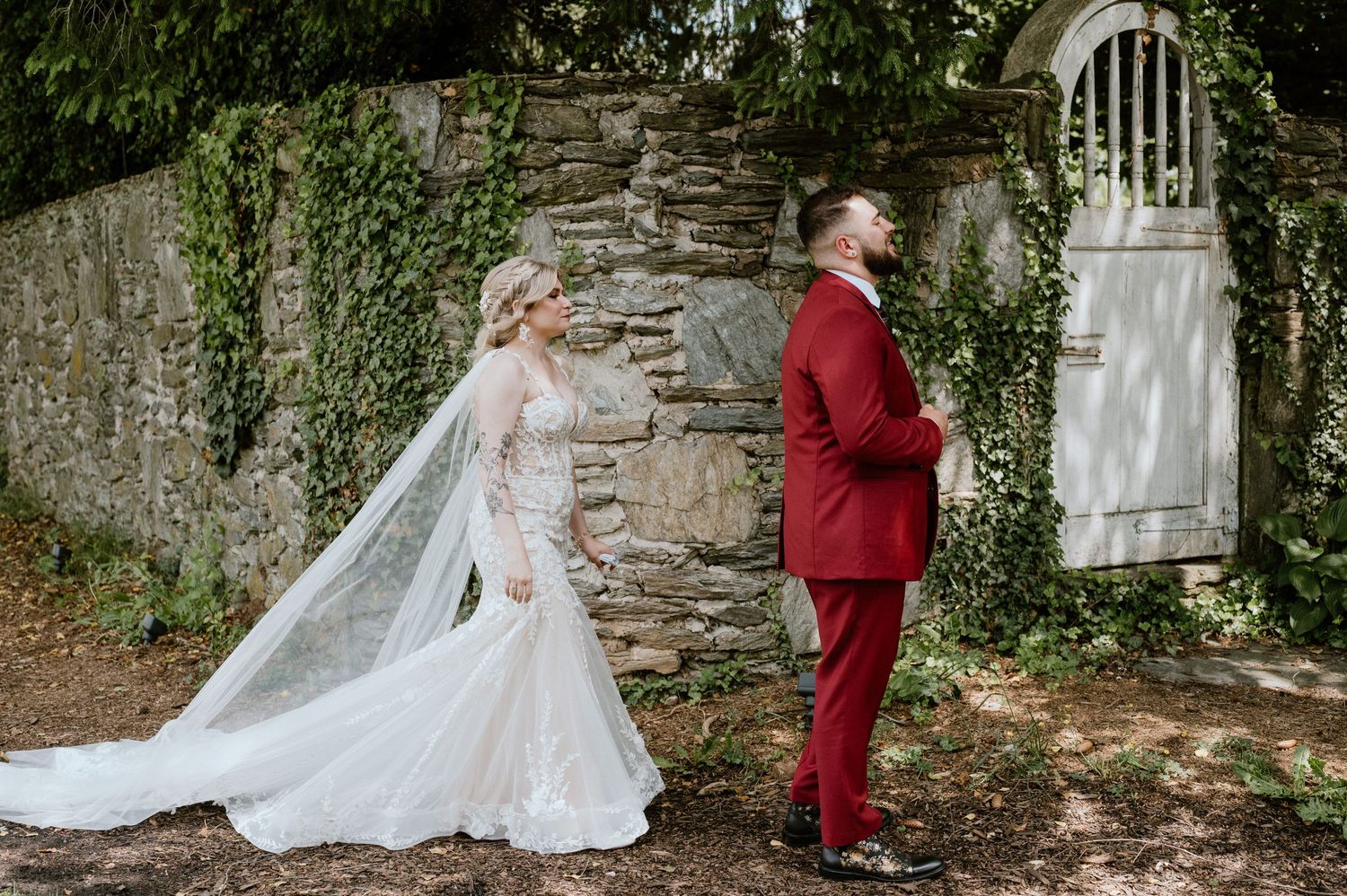 A romantic first look wedding moment against an ivy-covered stone wall.
