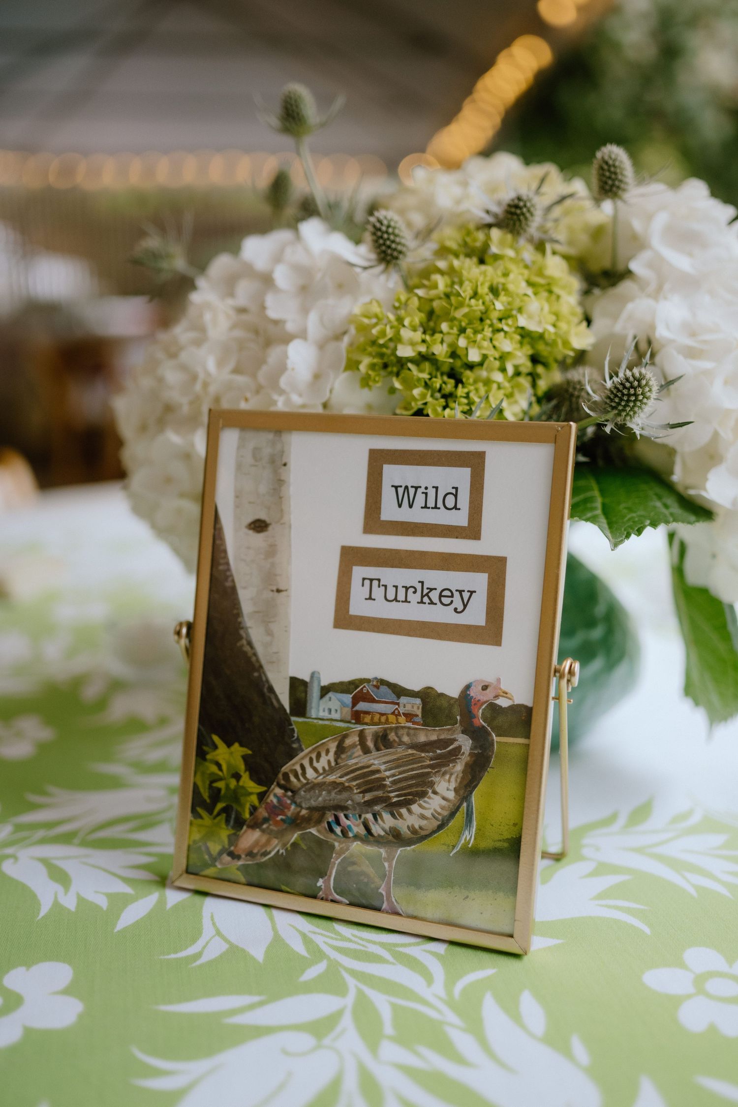 Table centerpiece with wild turkey artwork and white hydrangea flowers.