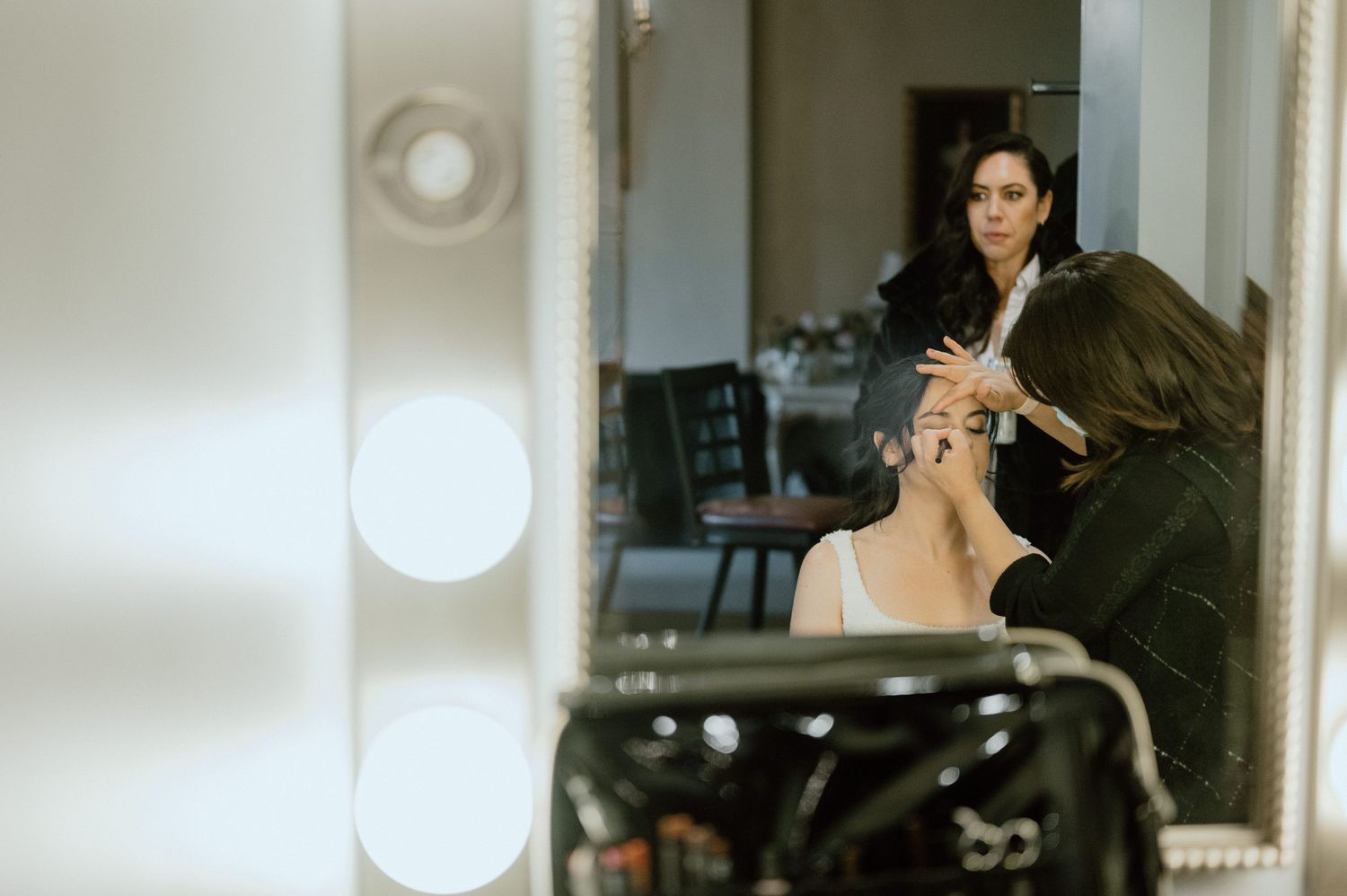 Behind-the-scenes image of wedding preparation with makeup artist at work.