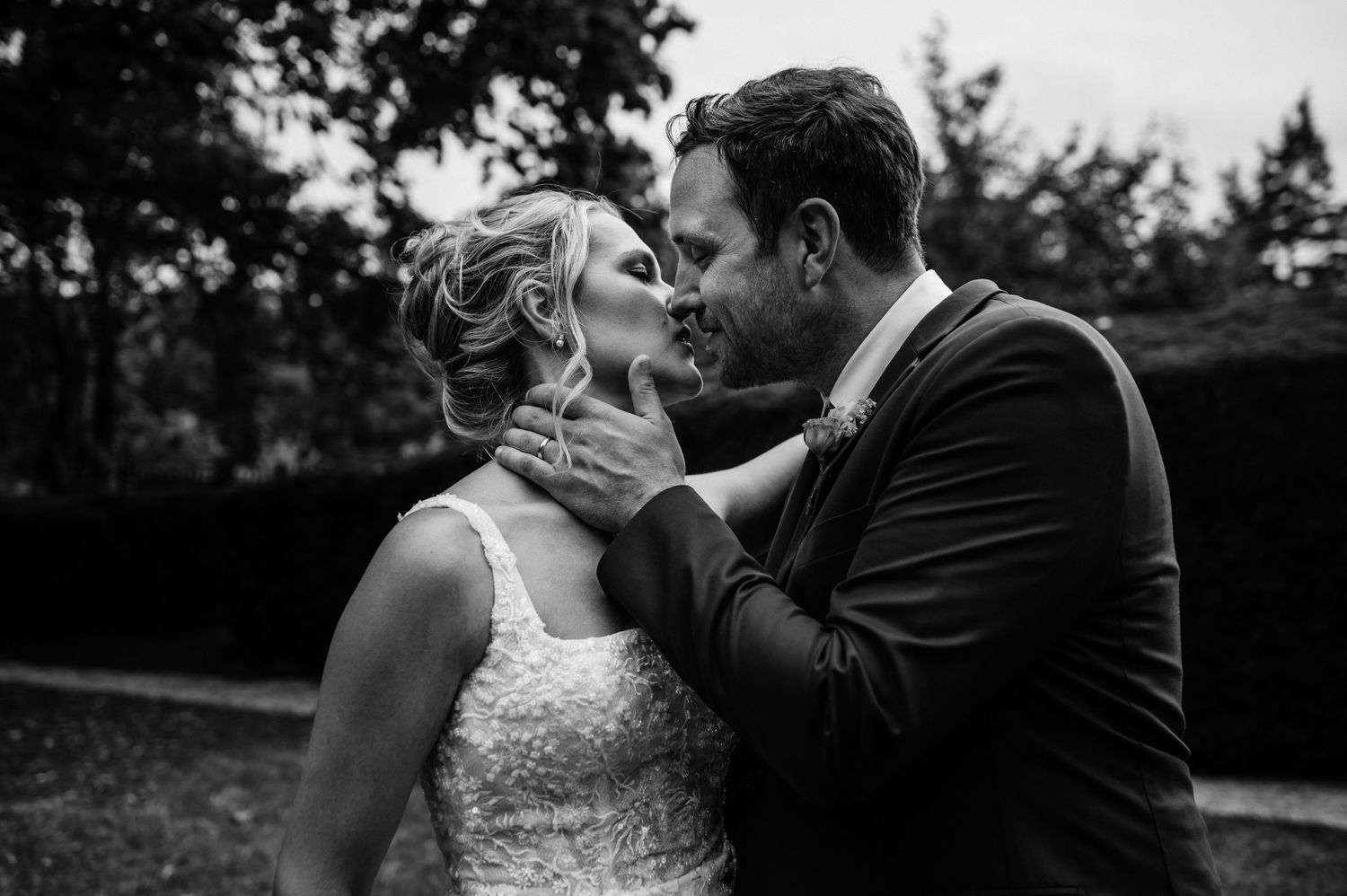 An intimate black and white moment between newlyweds in a garden setting.