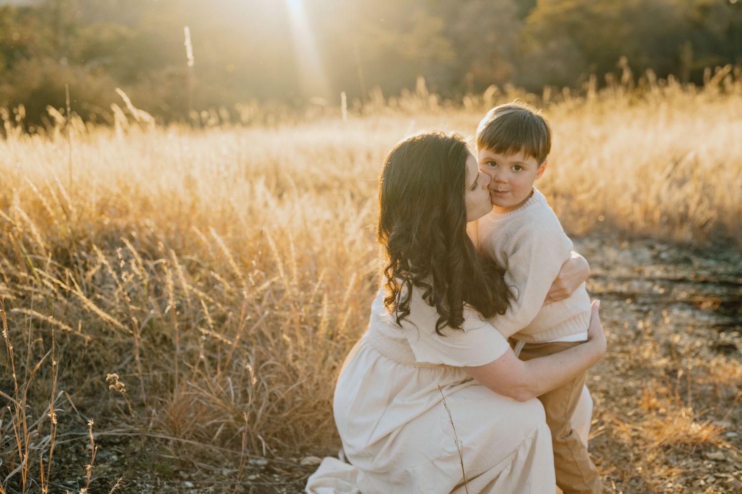 A romantic embrace between a couple in a golden field during magic hour.