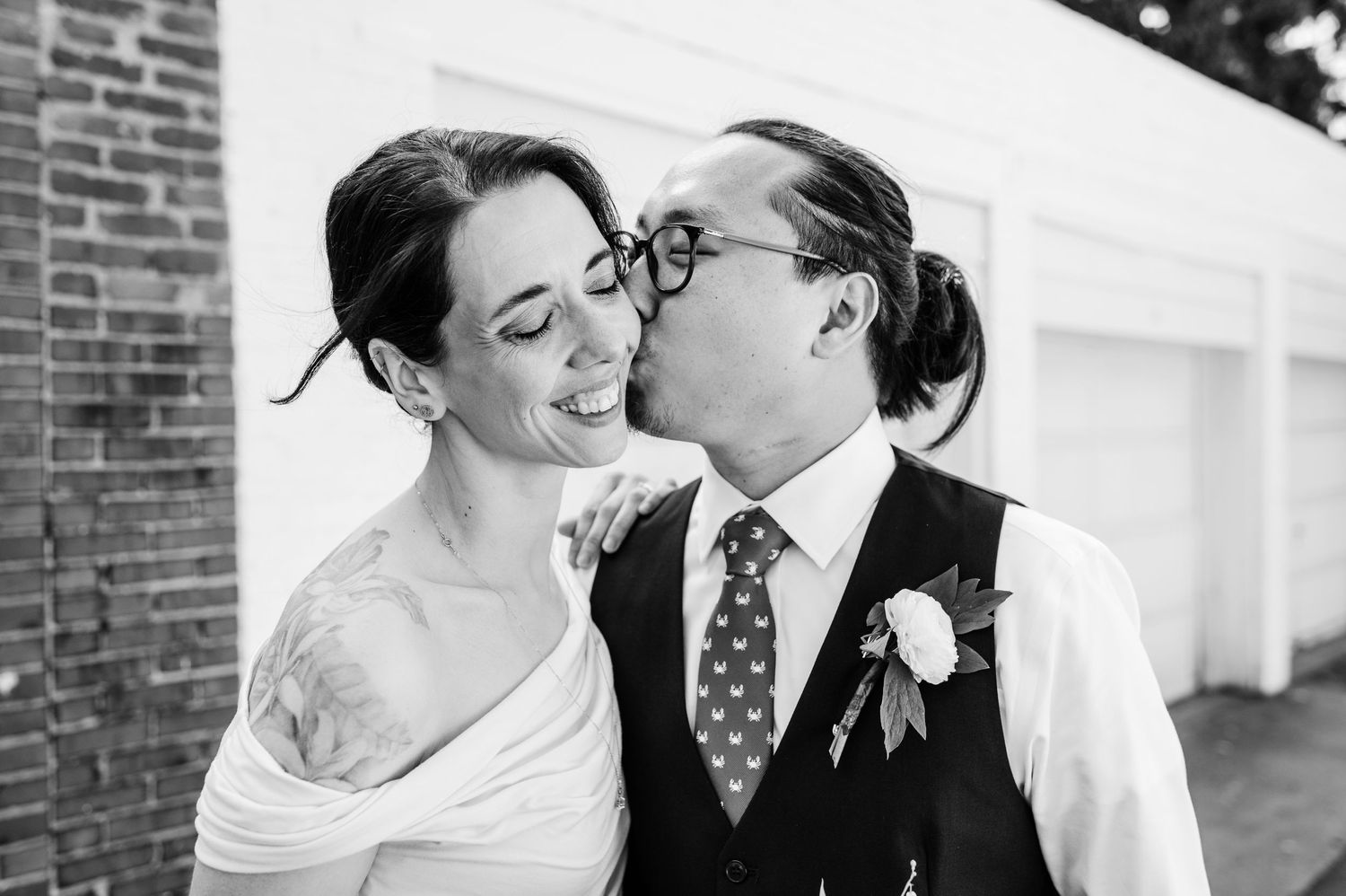 A black and white portrait of a couple sharing an intimate moment in formal wedding attire.