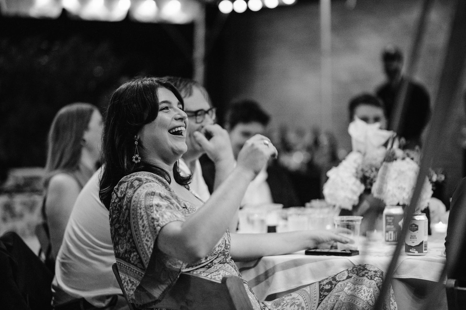 Guests enjoying laughter and conversation at a lively reception dinner under ambient lighting.