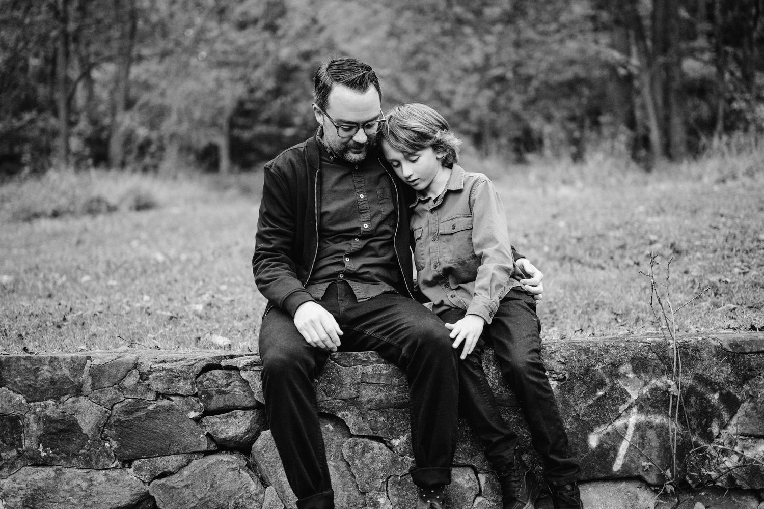 Black and white portrait of two people sharing a quiet moment on a stone wall.