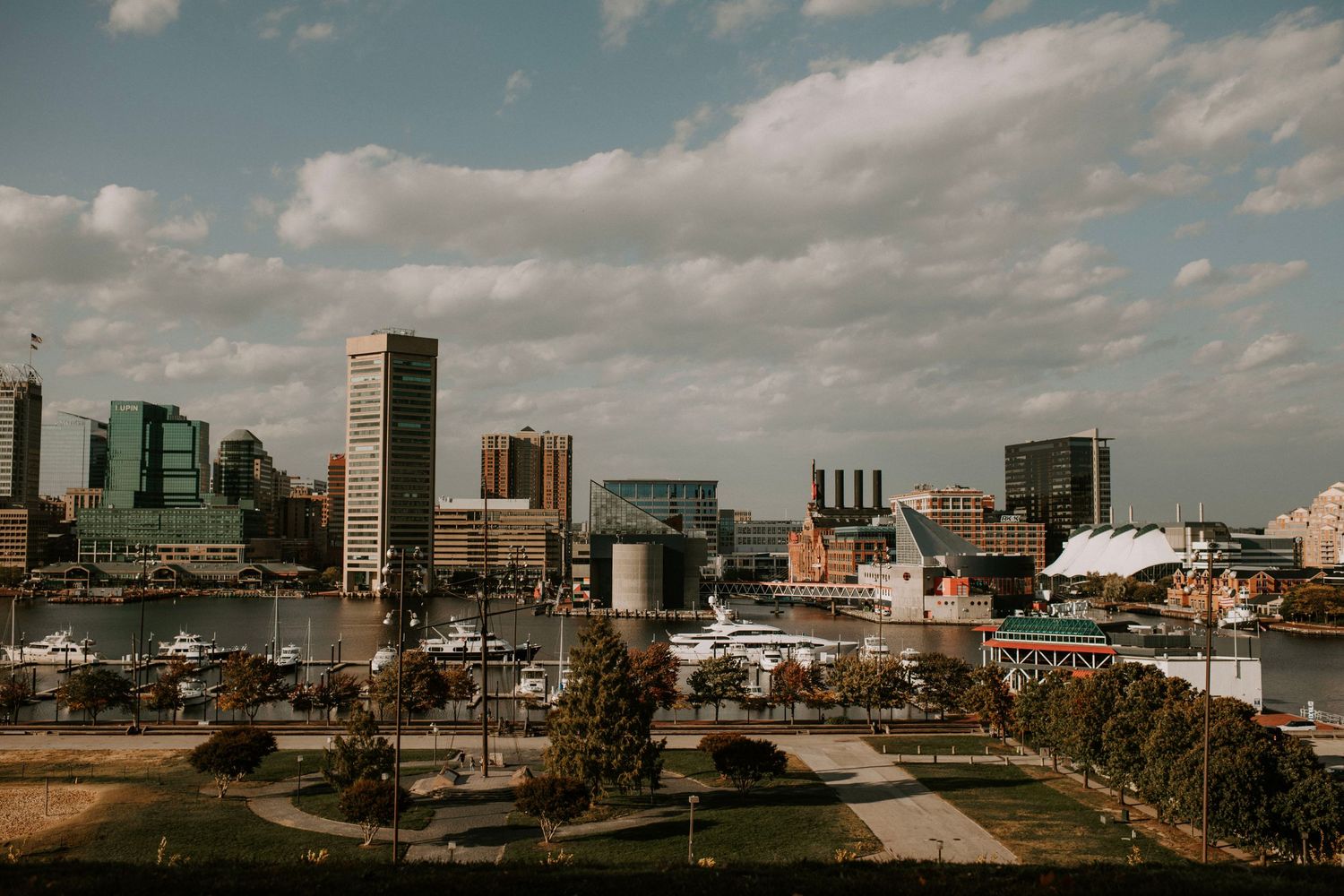 Baltimore city skyline view with harbor and industrial buildings under cloudy sky.