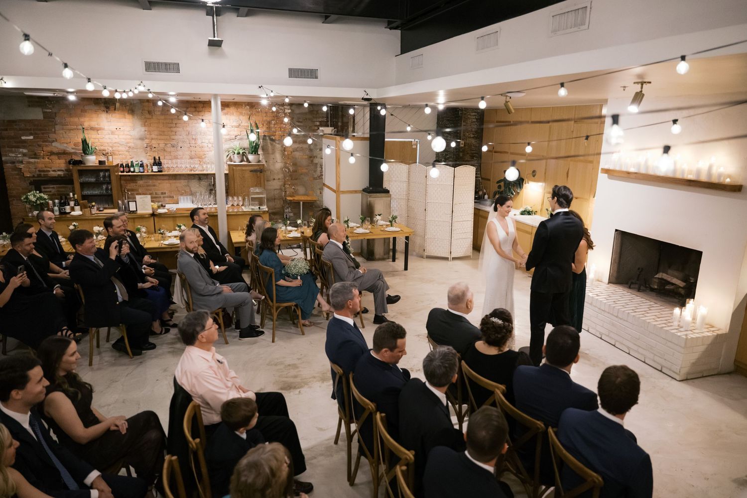 An intimate performance venue with wooden chairs arranged in rows facing a small stage area under modern track lighting.