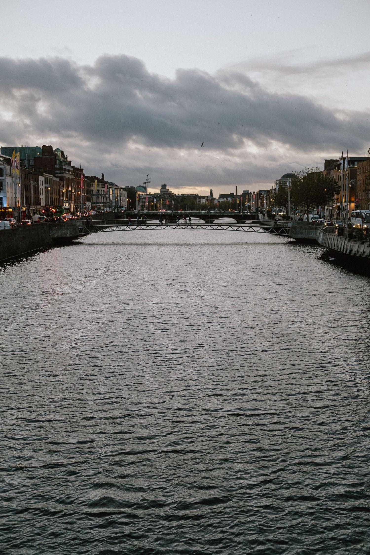 Dramatic cloudy sky over the River Liffey and Ha'penny Bridge in Dublin city center.