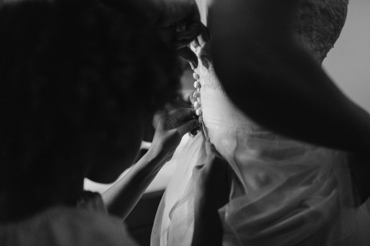 Close-up of wedding dress lacing being adjusted in dramatic black and white.