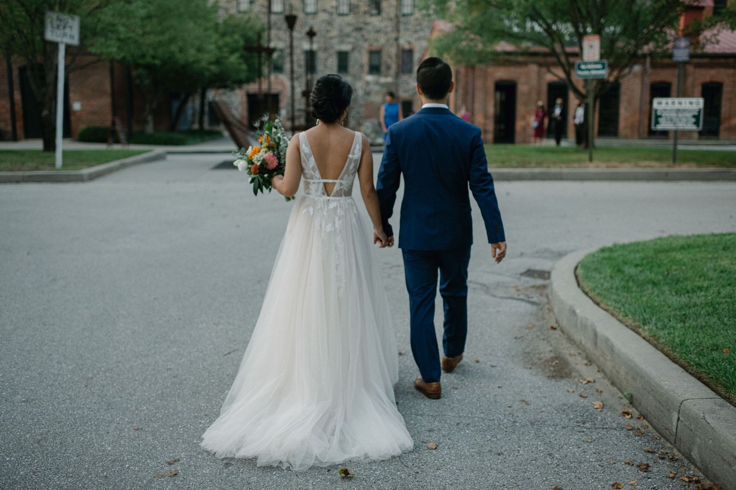 back of brides dress as couple walks back to wedding venue to meet family