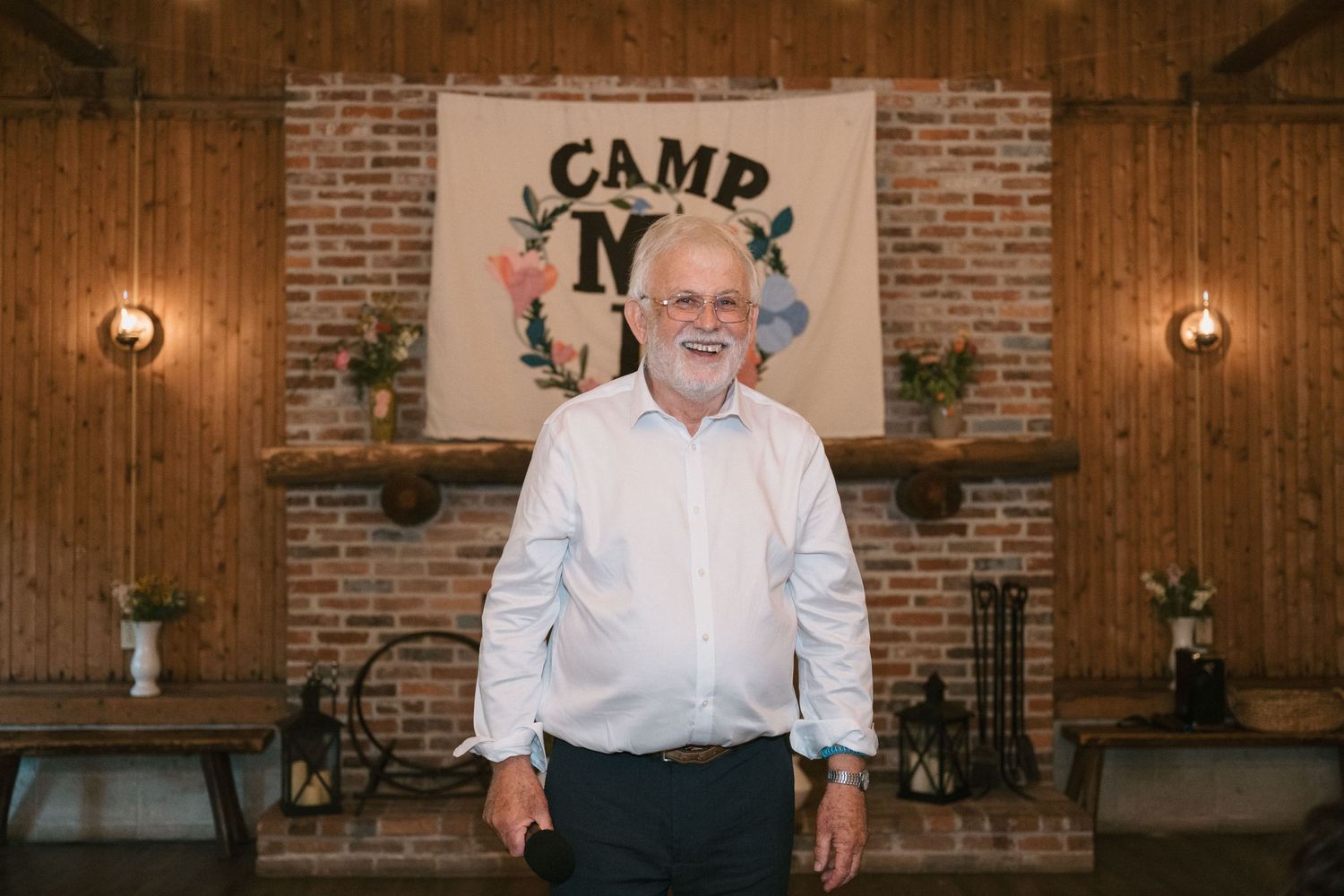 Interior of rustic venue with brick fireplace and Camp M sign on wall.