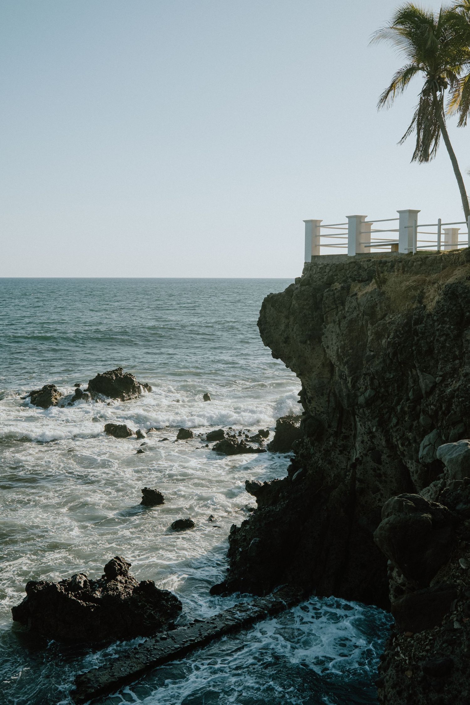 Wave splashing over a concrete post in the ocean during high tide.