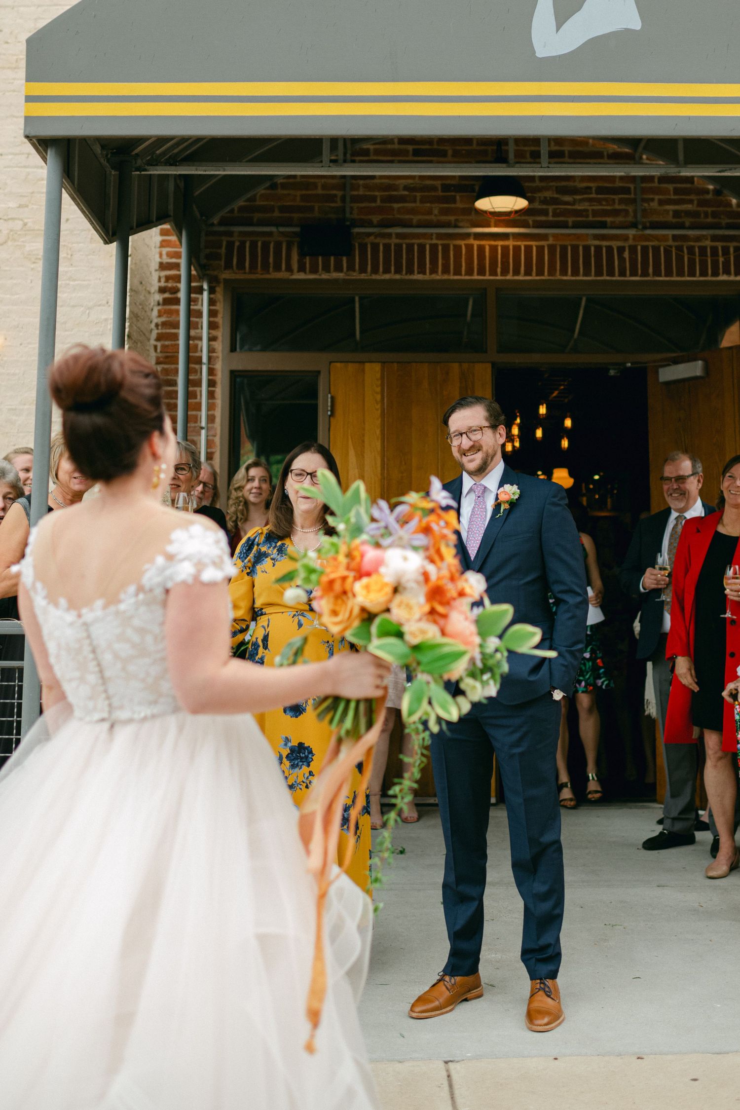 A first look moment between a couple with vibrant orange and yellow flowers.