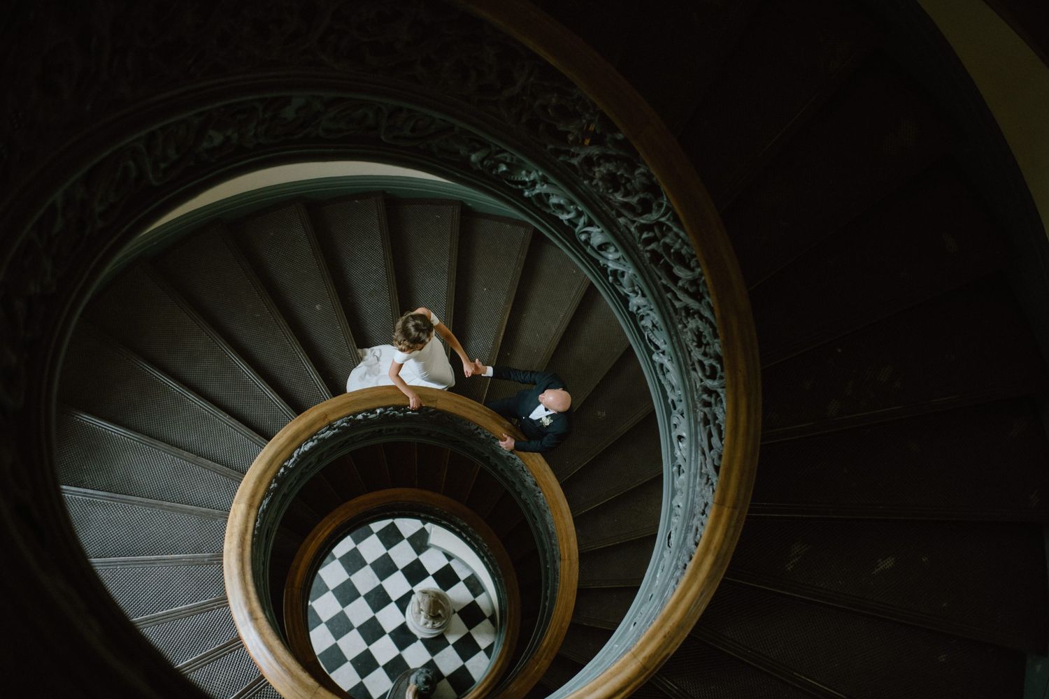 A spiral staircase with ornate details and checkered floor pattern photographed from above.