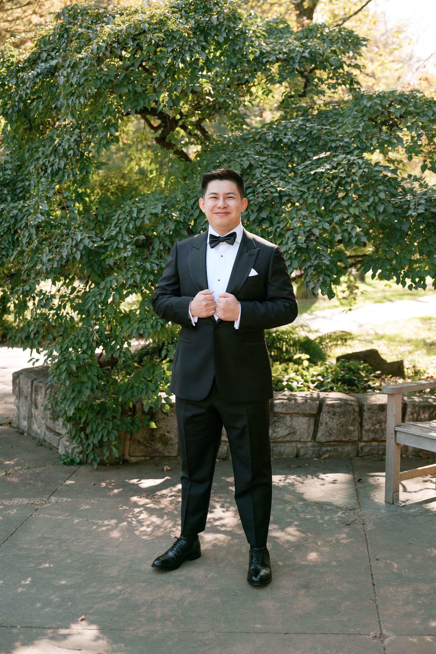 Sequence of a groom in a black tuxedo sitting on stone steps in dappled sunlight.