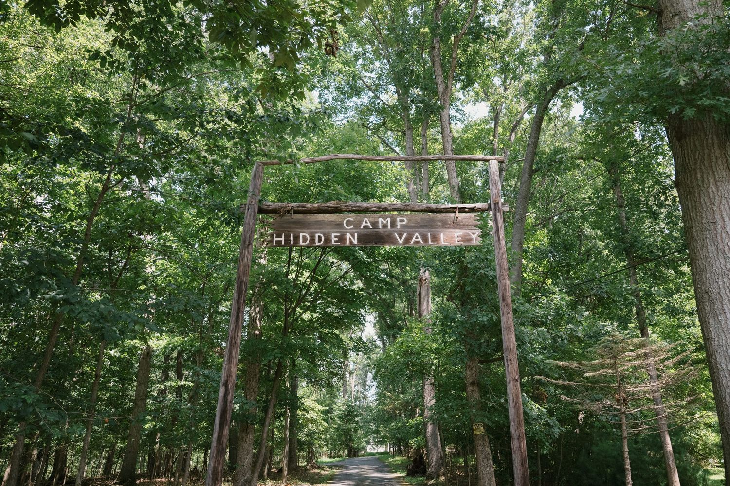 Wooden entrance gate with Hidden Valley sign surrounded by lush green forest.