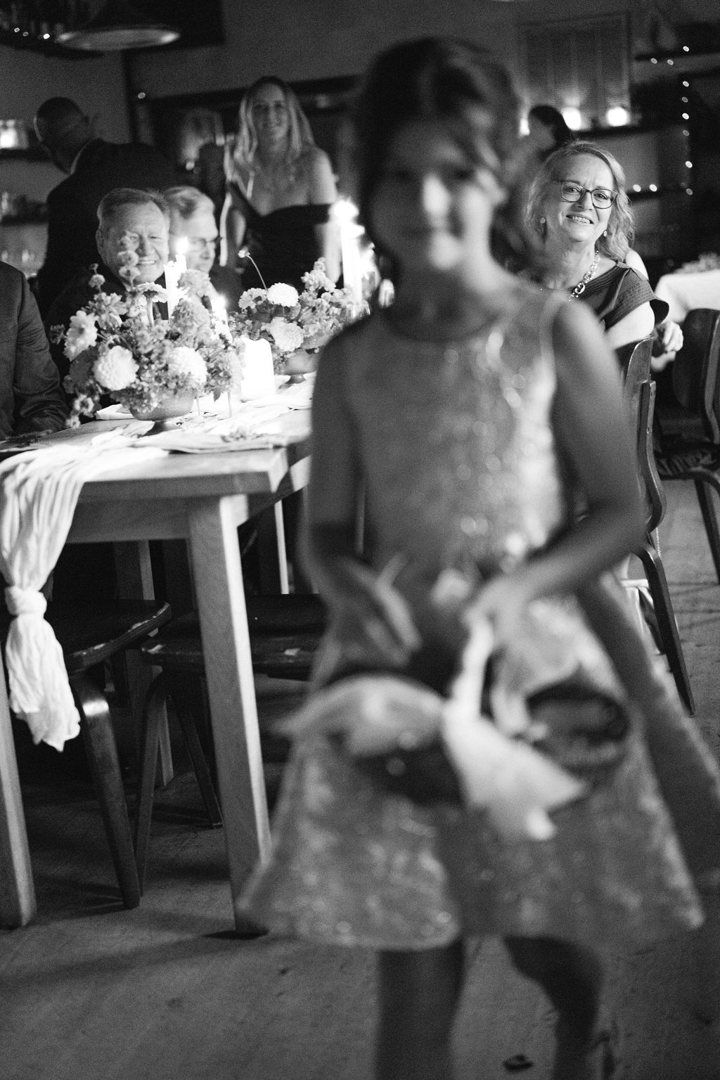 Wedding reception guests dancing together in a dimly lit venue with festive decorations.