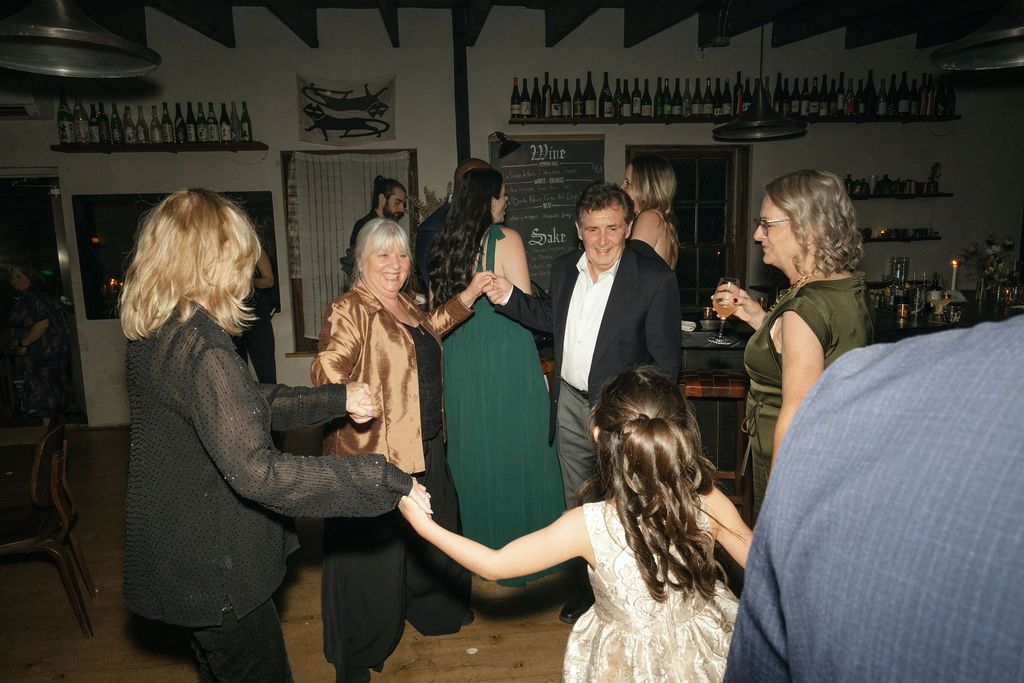 A lively group of party guests dancing and socializing in a rustic indoor venue Fadensonnon in Baltimore