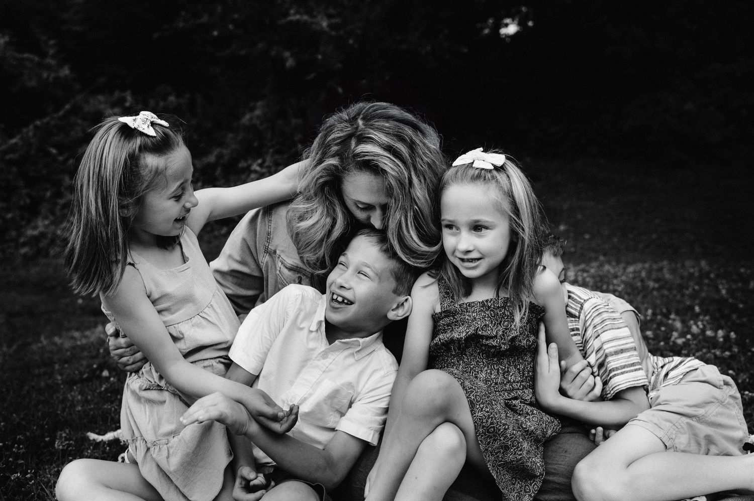 A candid black and white photograph showing joyful family interaction outdoors.