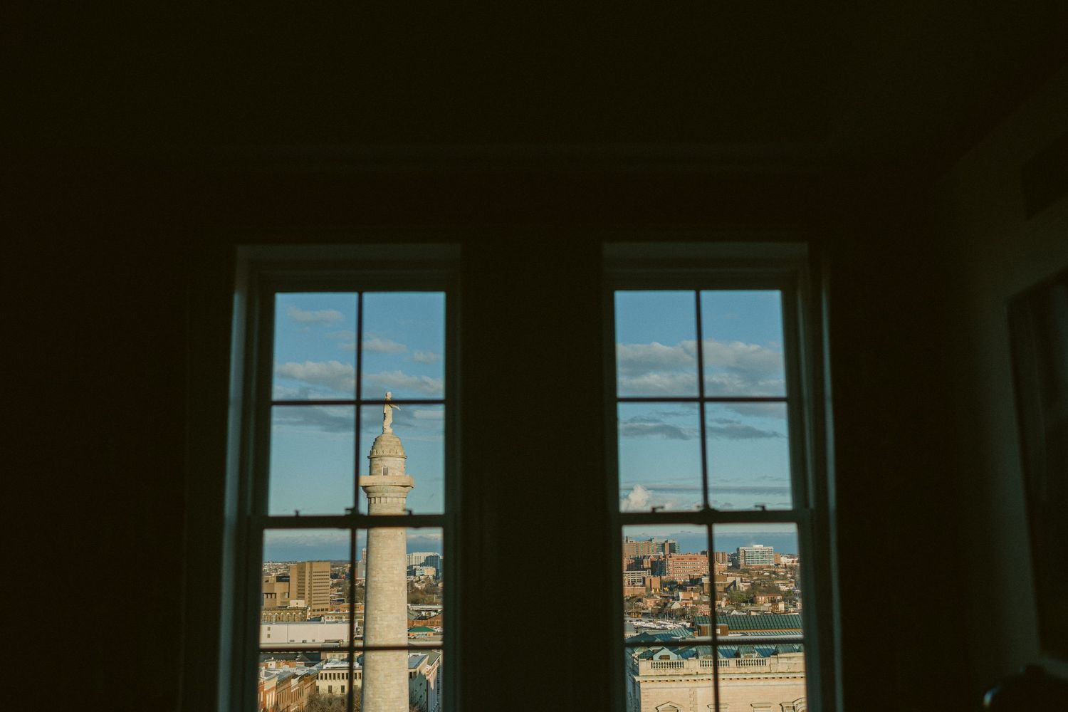 View of city buildings and monument through two arched windows.