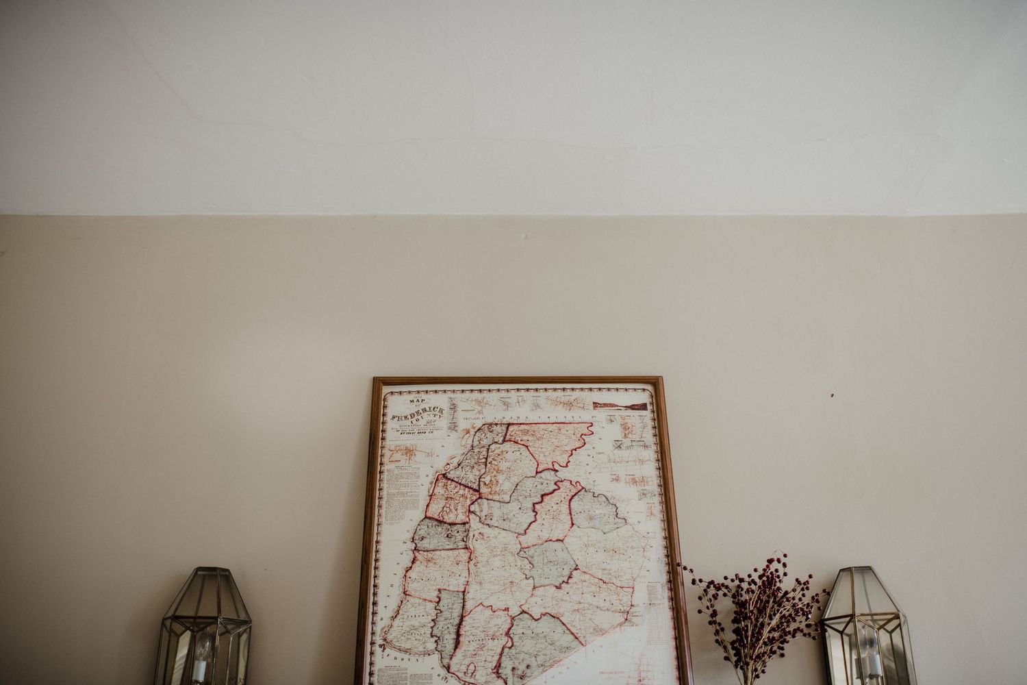 Framed vintage map and lanterns displayed on a white wall.