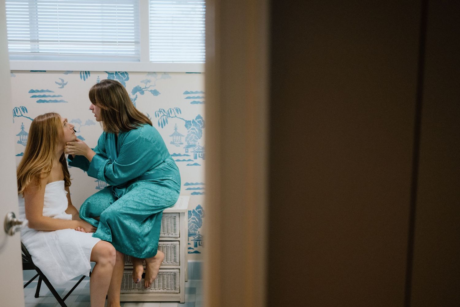 Two people share a close interaction against a wall with illustrated decorative patterns.
