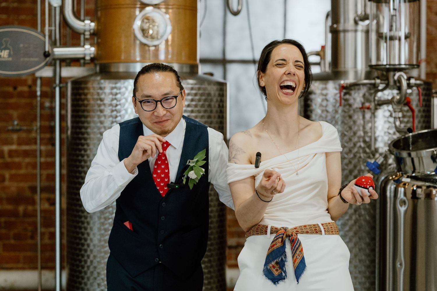 Playful moment shared between couples near stainless steel brewing tanks.