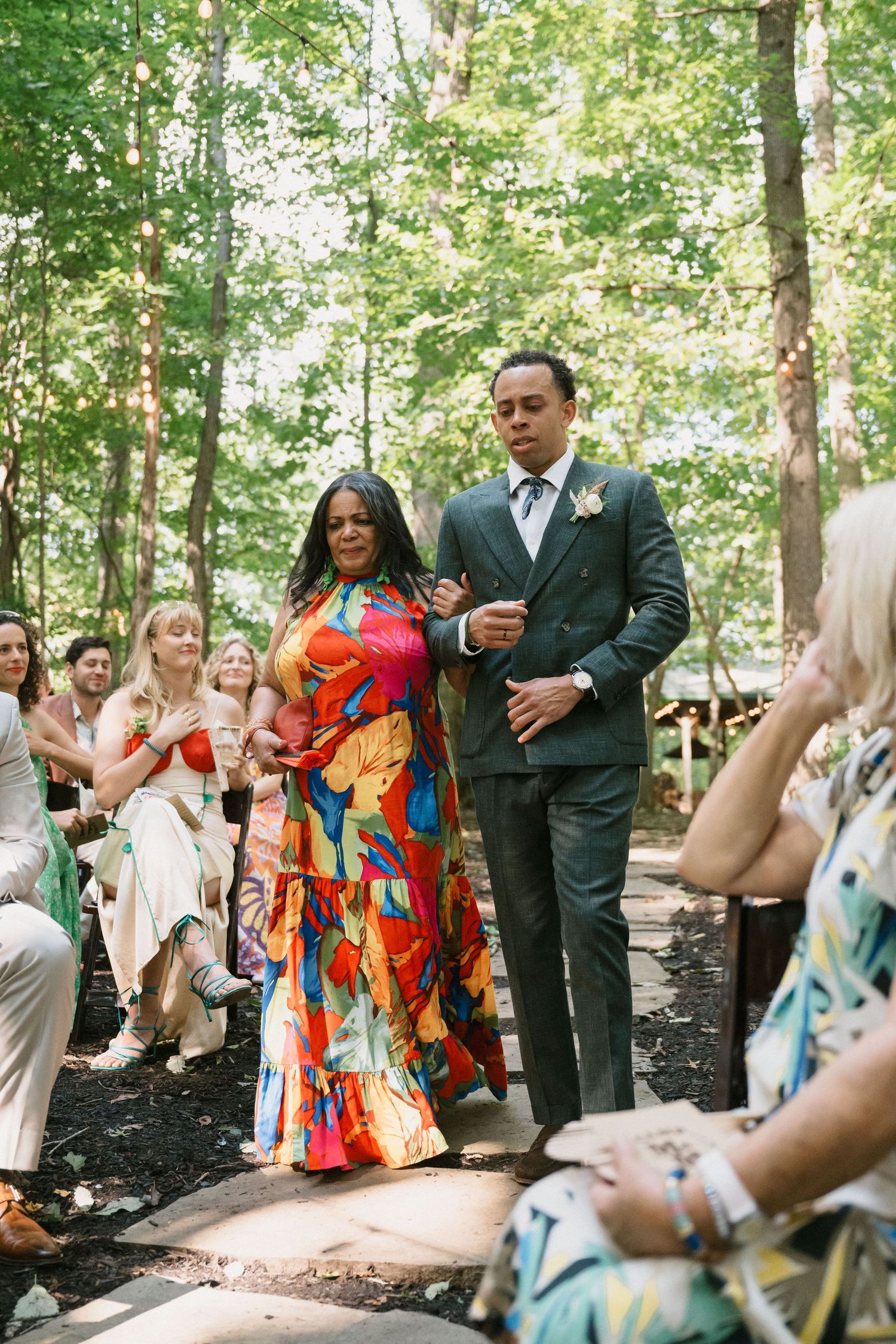 groom and mother walk together down the aisle