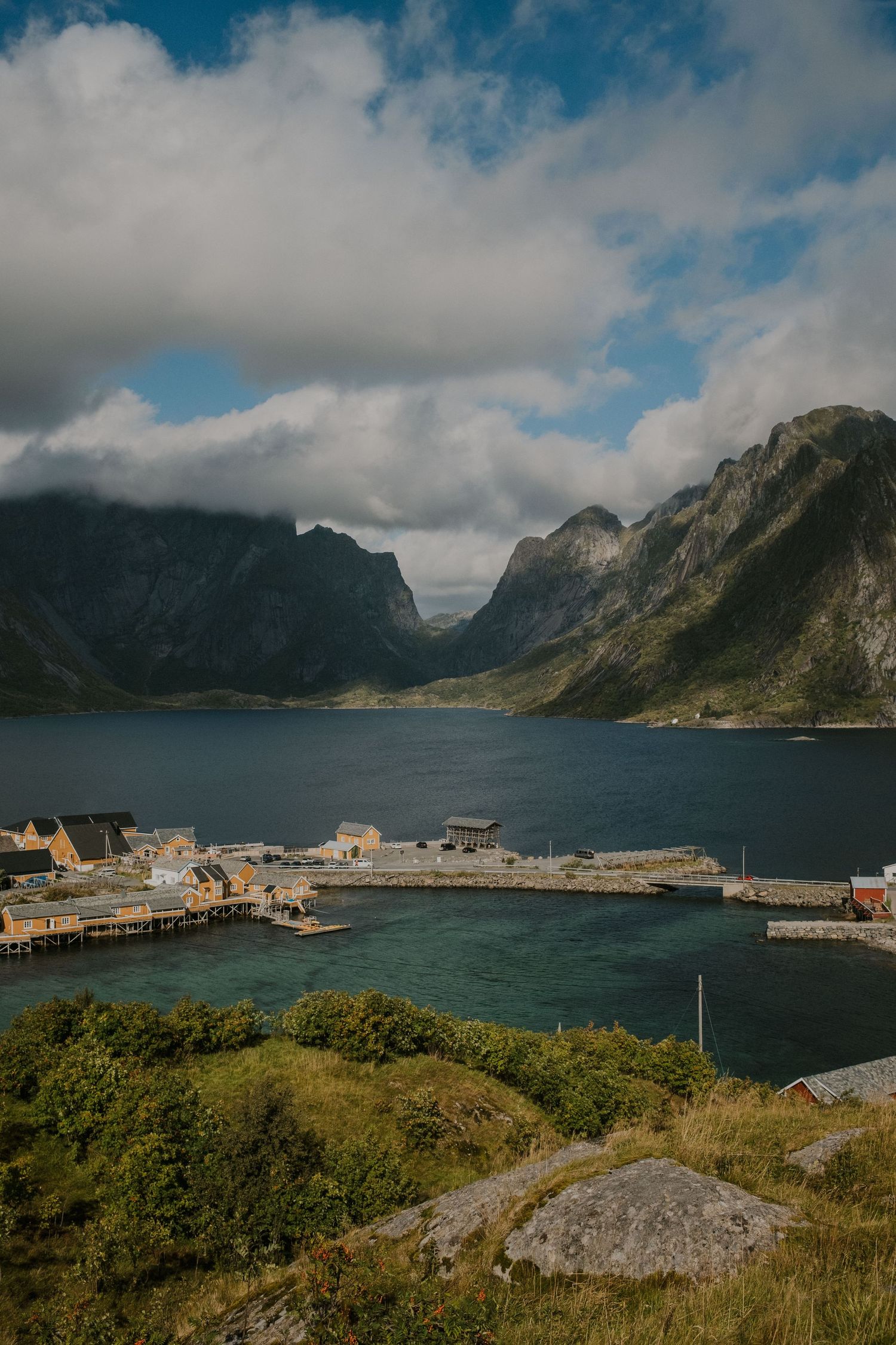 Picturesque fjord village surrounded by dramatic mountains with boats docked at wooden piers.