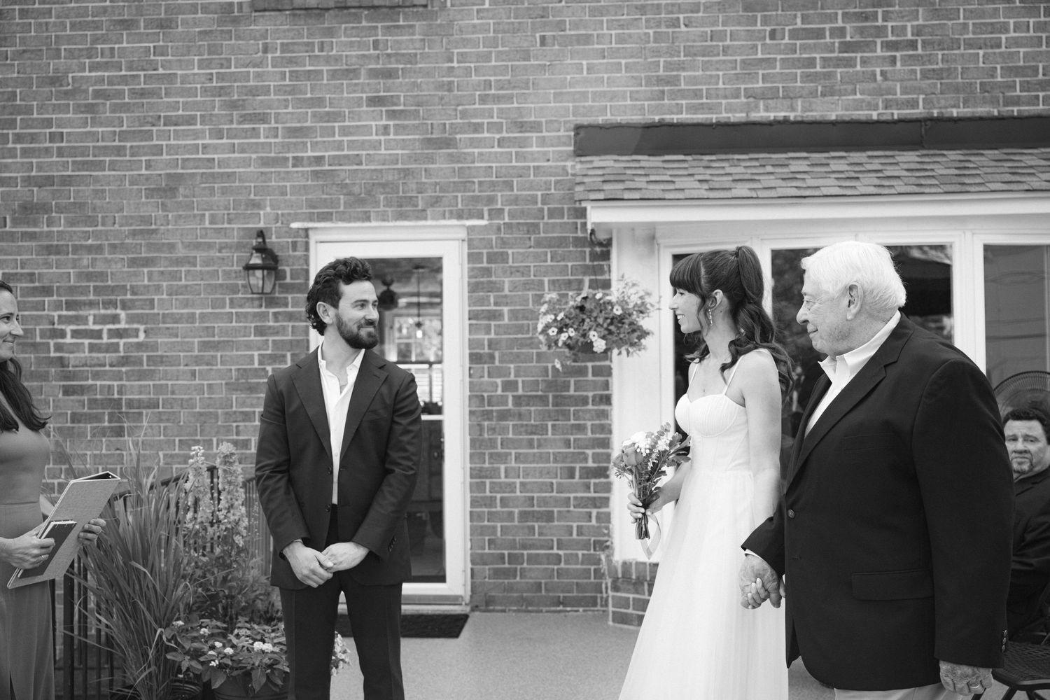Wedding party gathered outside a brick building during an intimate ceremony.
