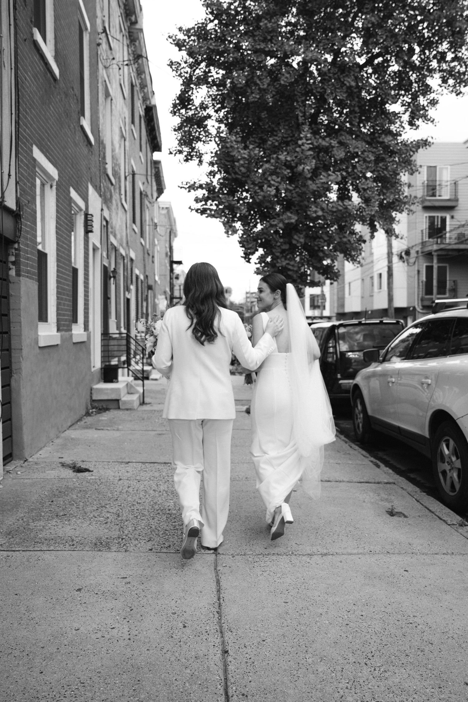 Black and white photo sequence of people walking down a city sidewalk in white outfits.