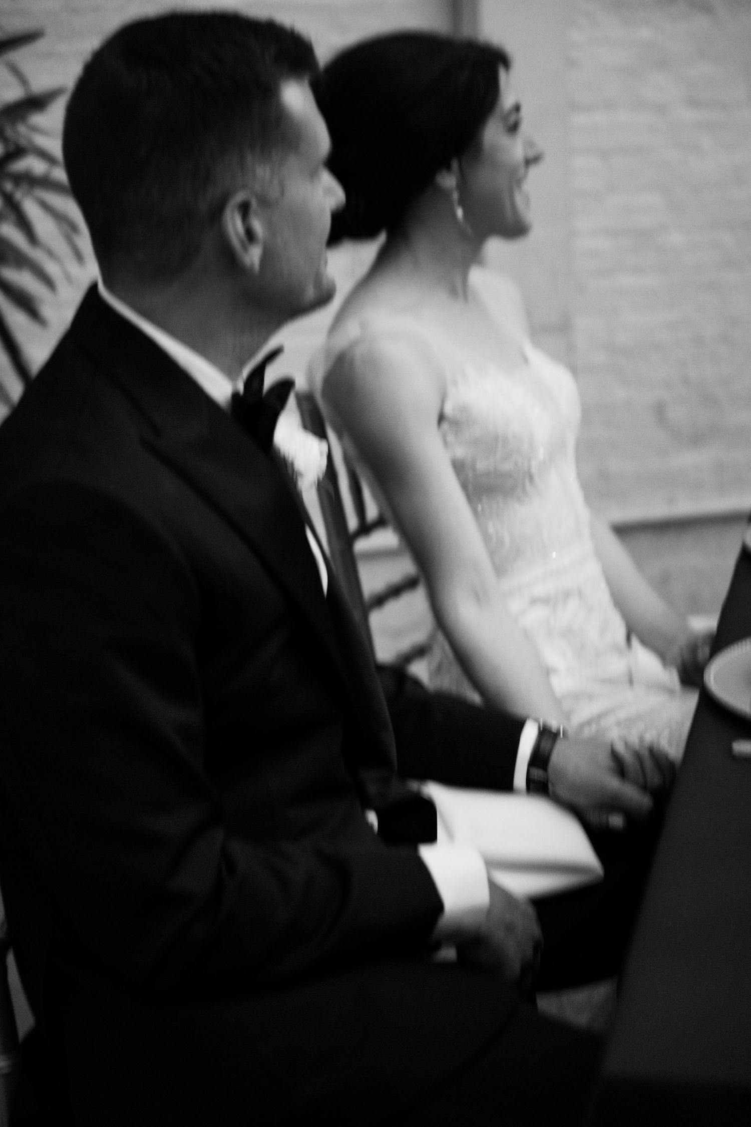 A black and white wedding photo of a couple sitting together during their ceremony.