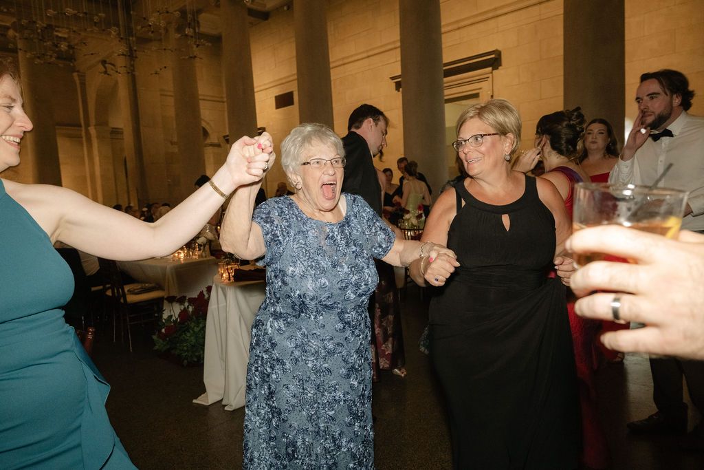 People dancing and socializing at an indoor event with warm lighting and elegant decor.