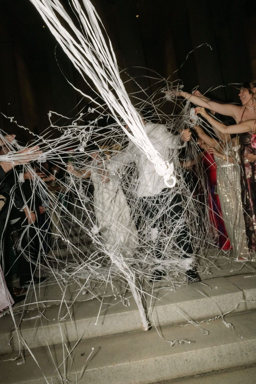 A sequence of photos showing a person breaking through a wall of white streamers in a dark room.