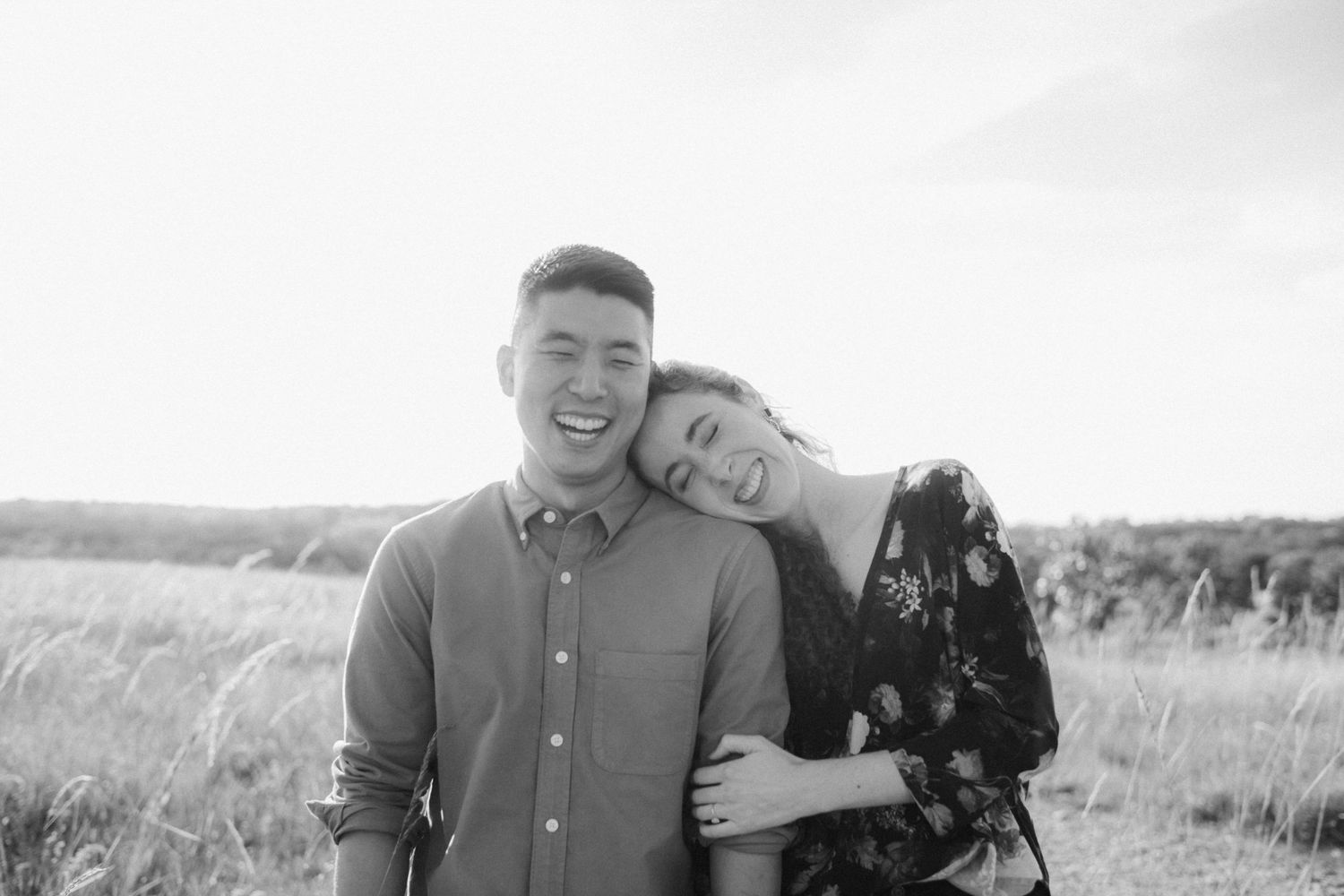 A joyful couple sharing an intimate moment in a sunlit field.