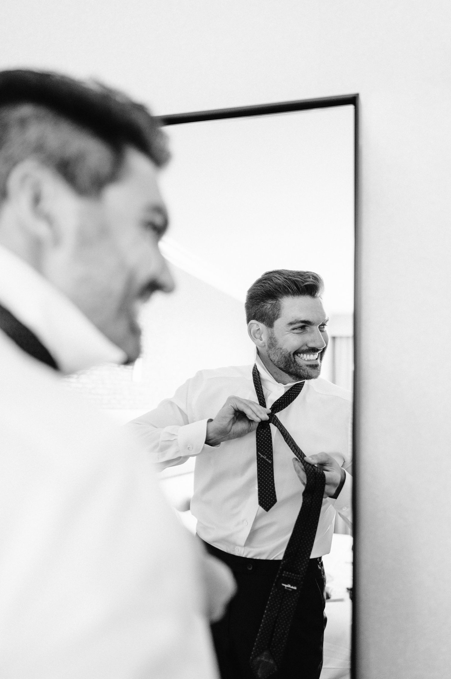 Artistic black and white mirror reflection sequence showing a man adjusting his tie.