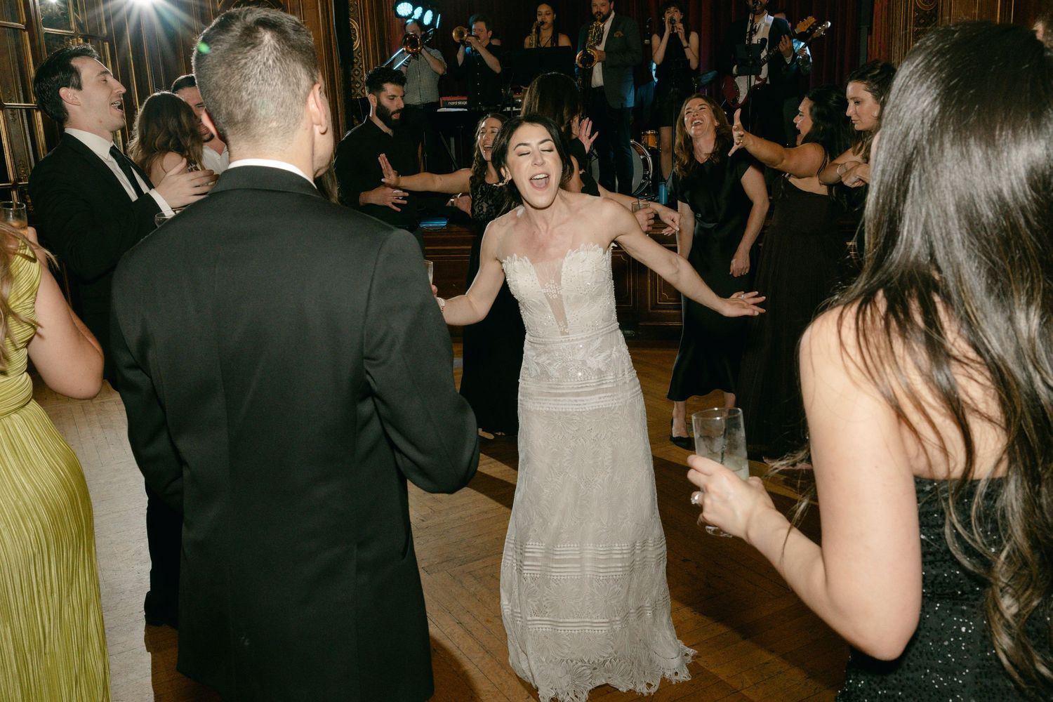 Party guests dancing and celebrating at a formal event on a dance floor with festive lighting and energy.