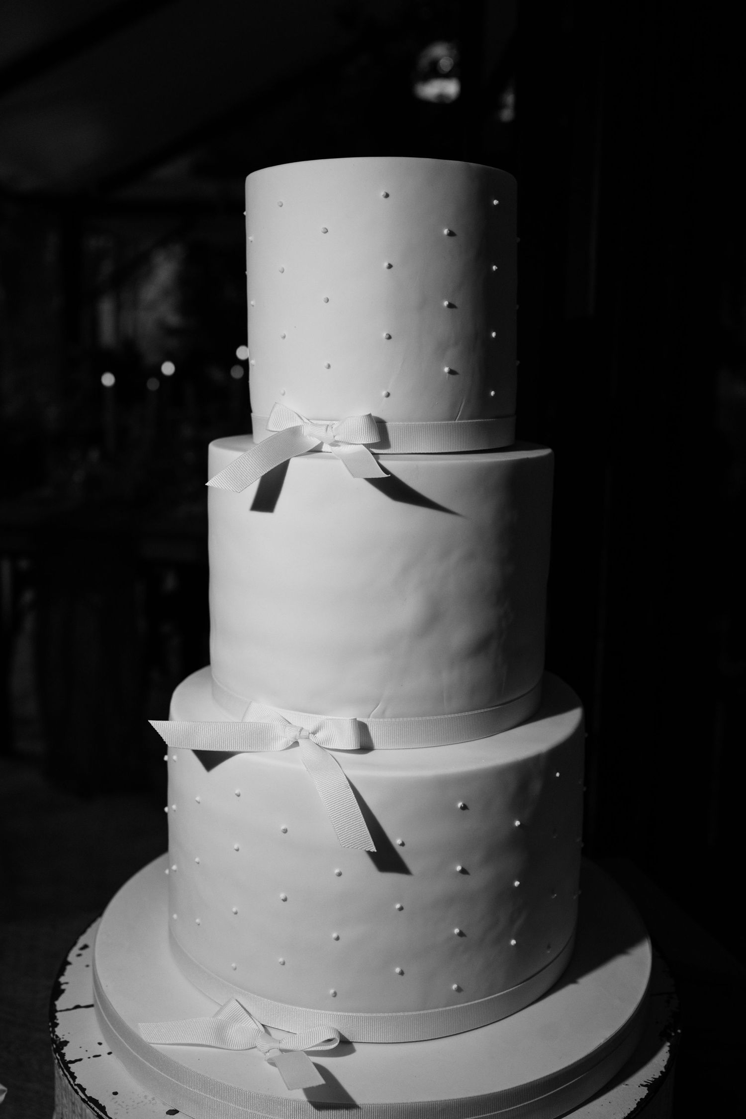 Classic three-tier white wedding cake with pearl dots and ribbon bow details.