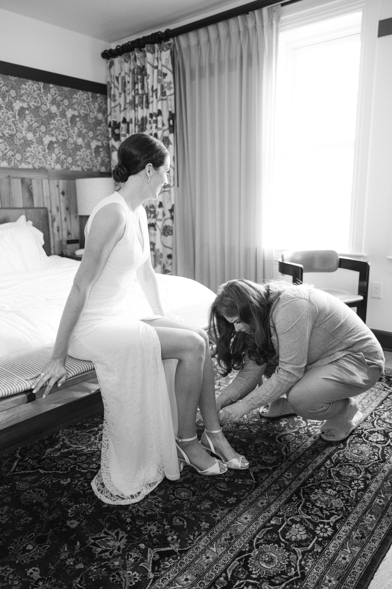 Black and white photo of wedding dress preparation with final touches being made before the ceremony.