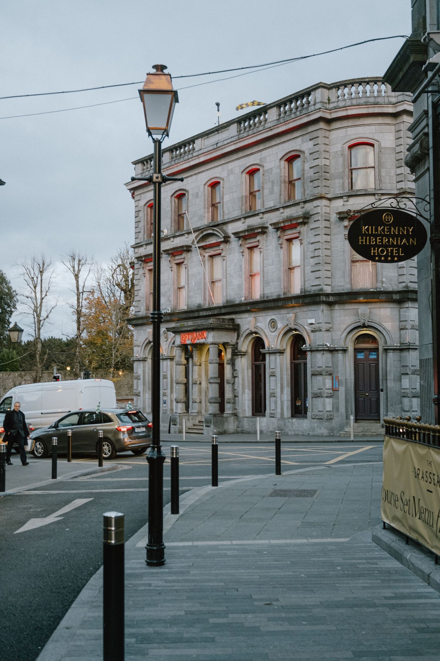 Historic stone building with ornate architecture and a vintage street lamp on a cloudy day in an Irish town.