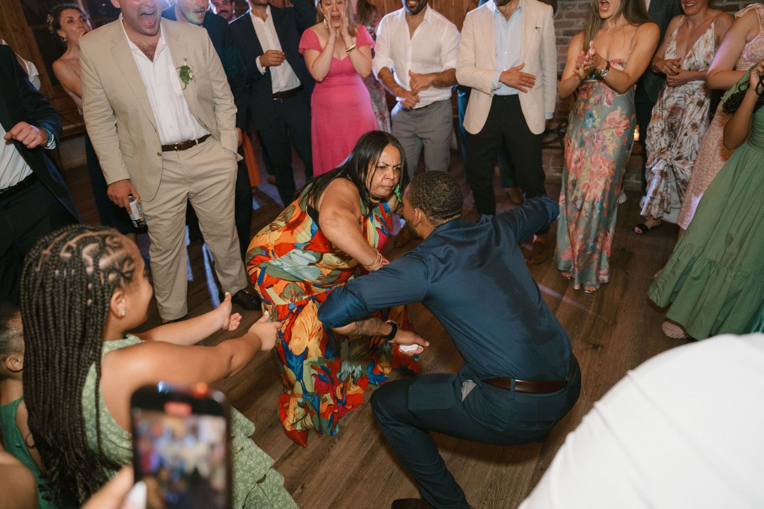 Wedding guests dancing and having fun on a wooden dance floor at a reception.