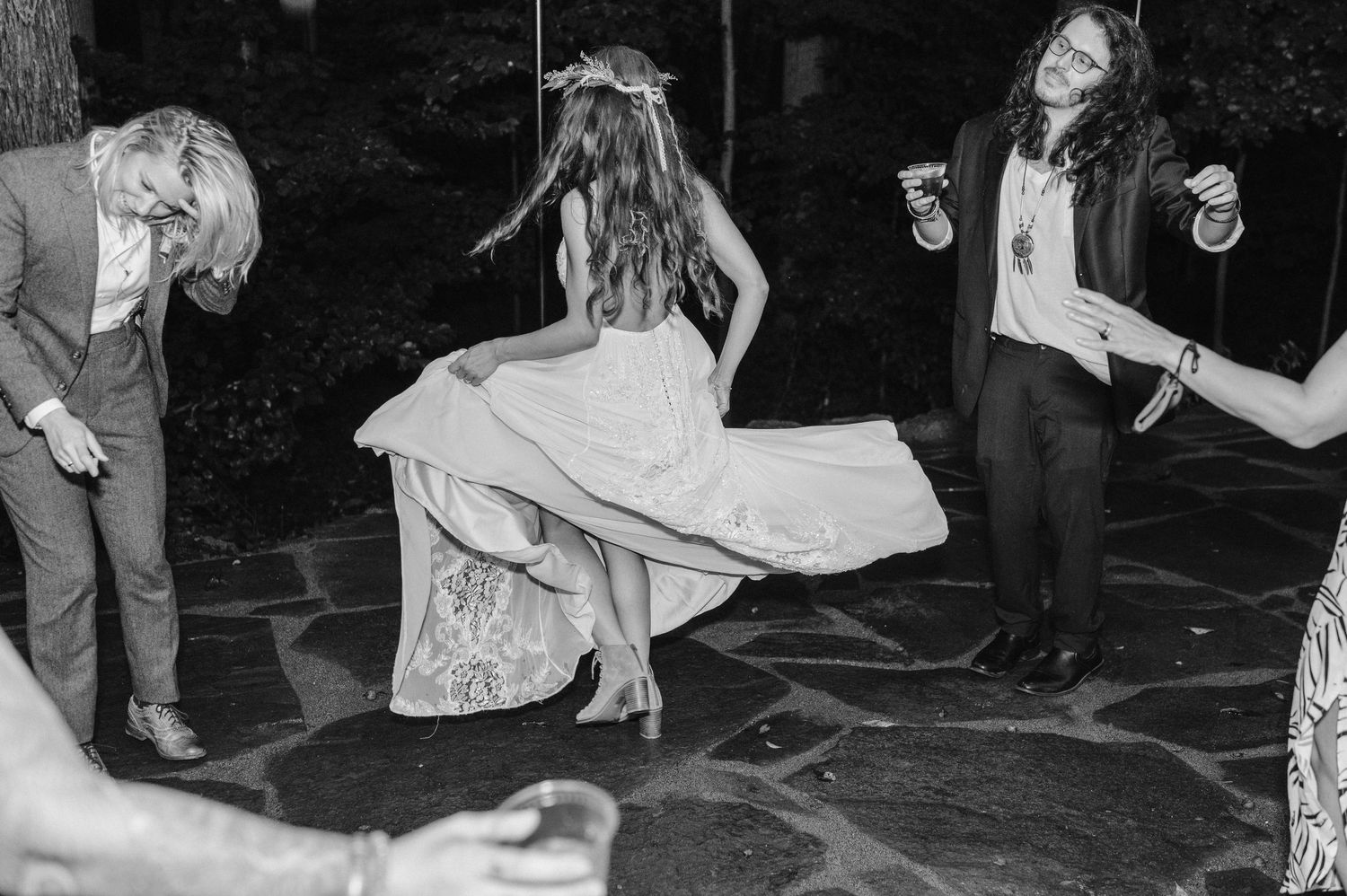 Black and white image of people dancing at an outdoor wedding reception.