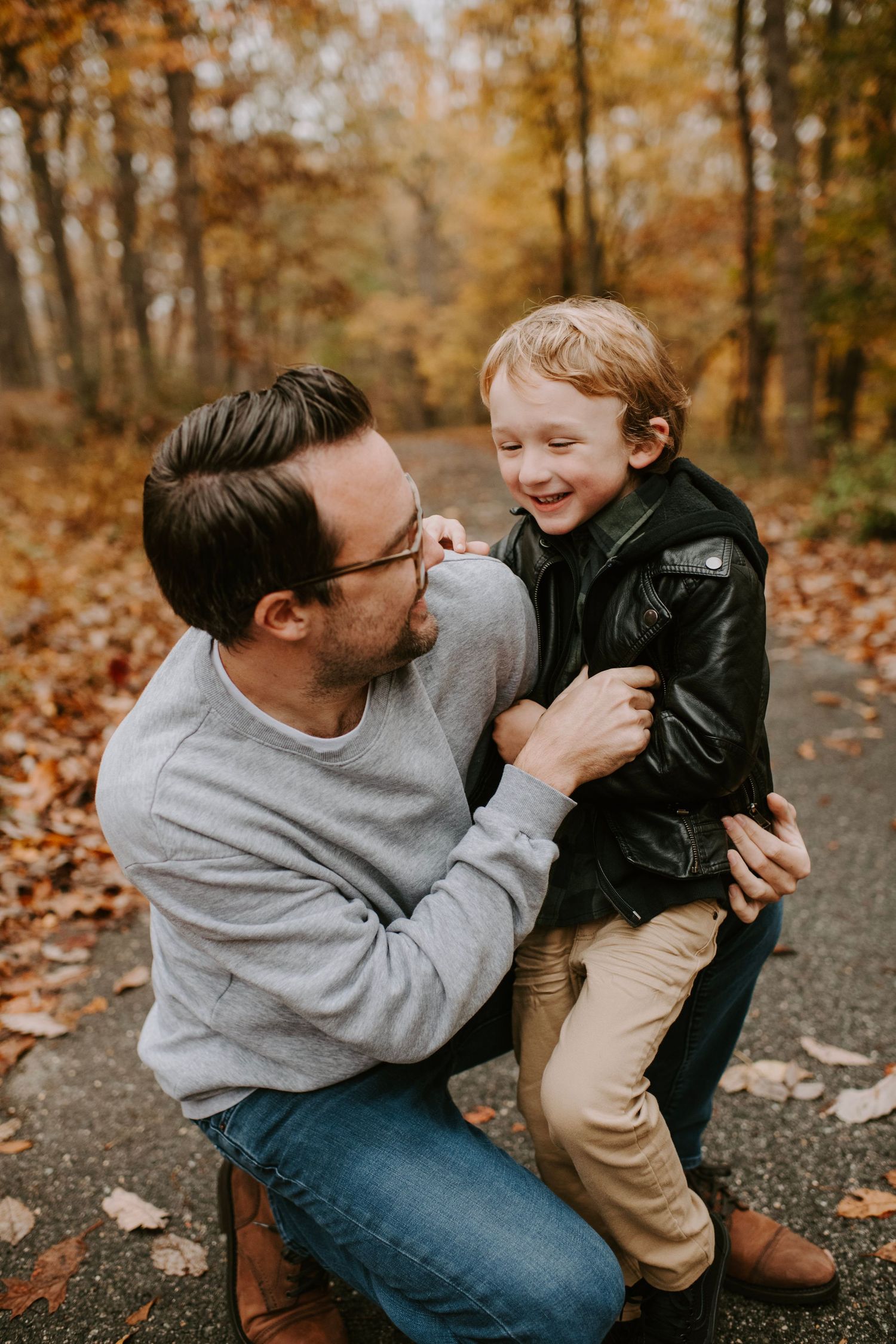Joyful moment shared on a fall forest trail covered in autumn leaves.