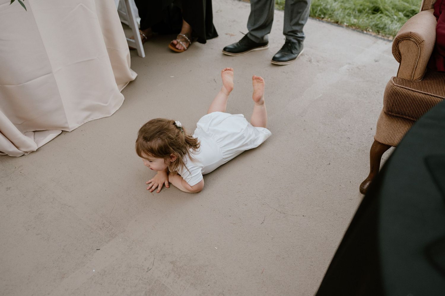 Young child lies on dance floor during wedding reception surrounded by guests.
